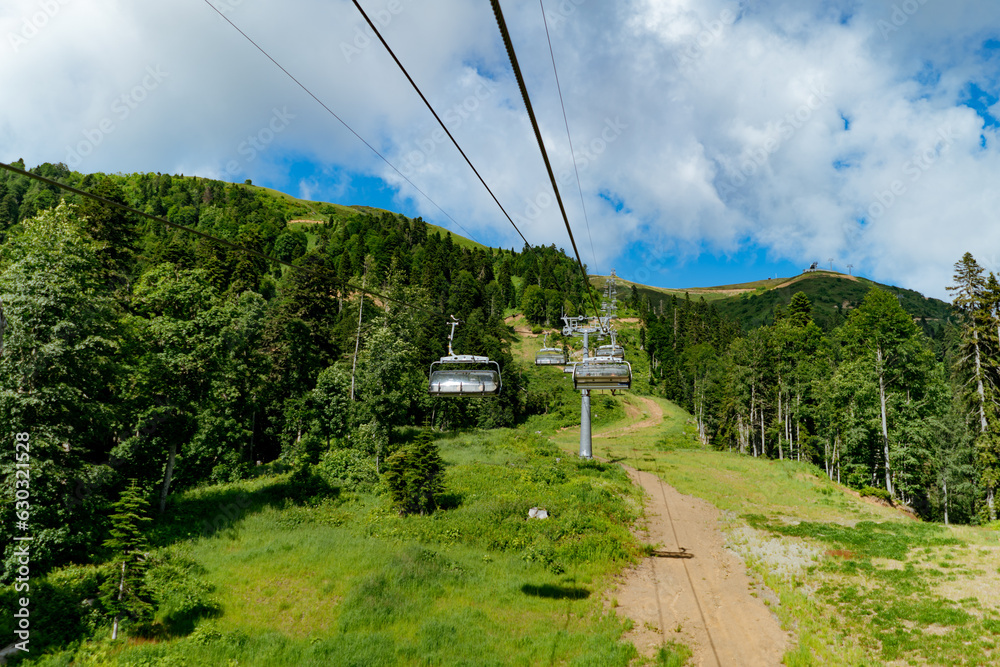 Modern rope way cabins with people against blue sky and mountain tops. Rosa Khutor, Soschi, Russia Modern rope way cabins with people against blue sky and mountain tops. Rosa Khutor, Soschi, Russia