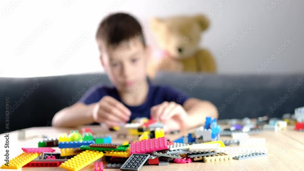 child, kid plays with colored plastic parts of the constructor, creates buildings, equipment, transport, the concept of the development of creativity, fine motor skills, patience and perseverance child, kid plays with colored plastic parts of the constructor, creates buildings, equipment, transport, the concept of the development of creativity, fine motor skills, patience and perseverance