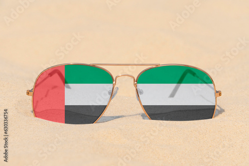 Sunglasses with glasses in the form of the flag of United Arab Emirates lie on the sand. The concept of summer holidays, travel and tourism in United Arab Emirates photo