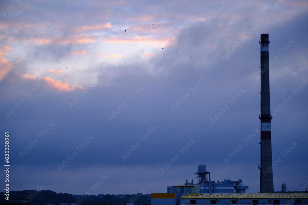 Fototapeta premium Industrial pipe on the background of blue thick clouds. Evening time