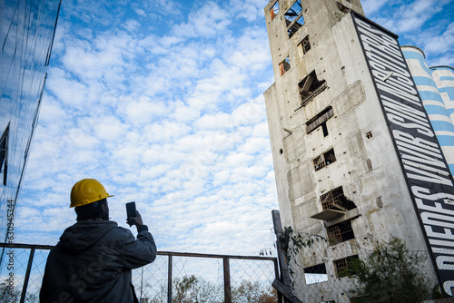 rear view of male engineer taking a picture with his phone to a ruined building