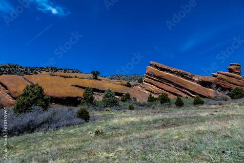 Scenic view of a grassy hill with a variety of rocky formations and trees