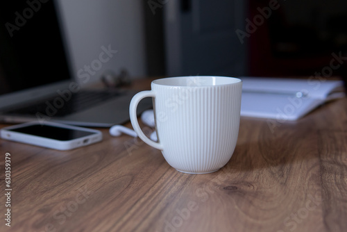 a cup of coffee close-up on the background of a laptop and a notepad with a pen. coffee break composition during work.