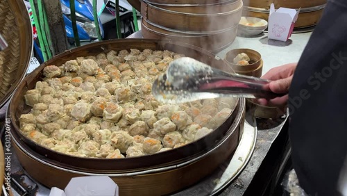 Street food booth selling traditional dumpling named Dim Sum with piles of bamboo steamer steaming the dumpling