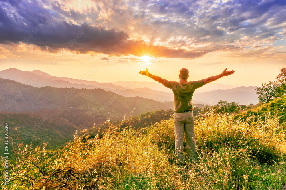 rejoicing man with beautiful scenic mountain sunset landscape on background. happy man watching amazing evening sunset rejoicing man with beautiful scenic mountain sunset landscape on background. happy man watching amazing evening sunset