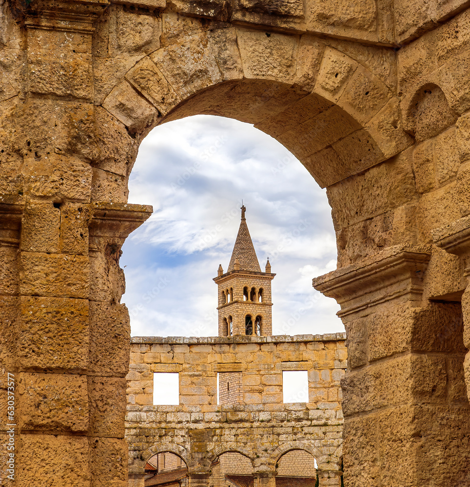 old arch of ancient historical building with walls and beautiful high tower with blue sky on background