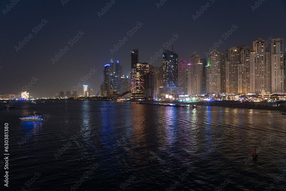 Obraz premium View of the skyline of Marina dubai with business and residential towers and the Marina beach illuminated at night, Dubai, UAE
