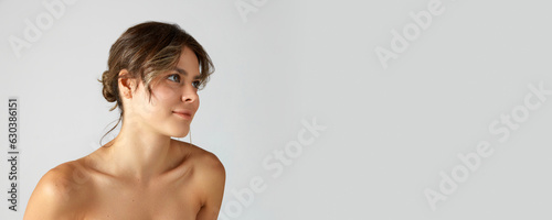 фотографія Elegant, beautiful young woman with smooth, healthy, perfect skin and bare shoulders on grey studio background