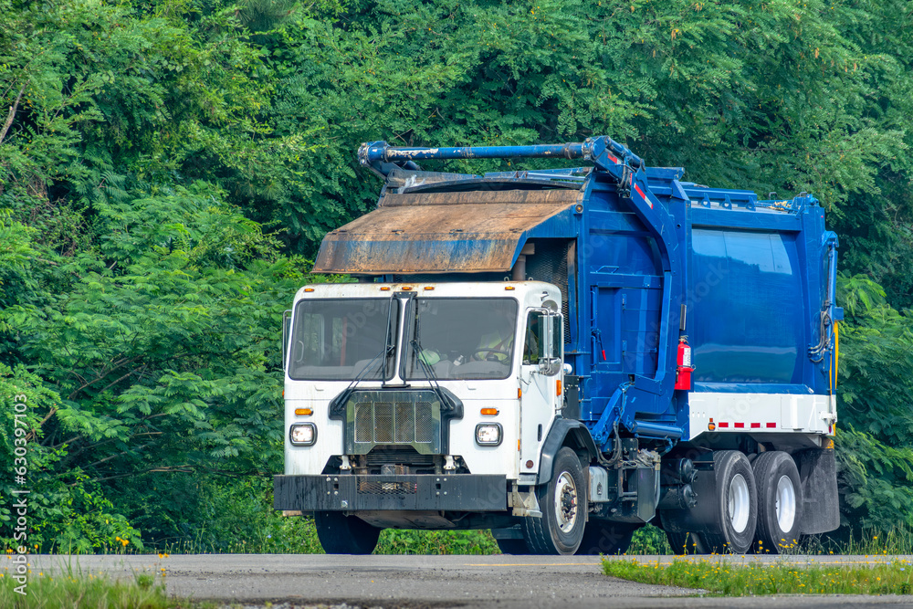 Blue and White Garbage Truck On The Highway