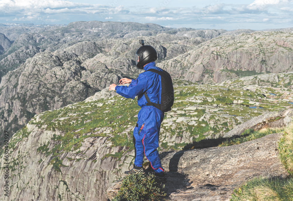 Male skydiver standing on top of a mountain and is going to jump