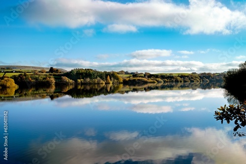 Tranquil lake reflecting the white clouds in the sky  creating a peaceful atmosphere. Bolton  UK.