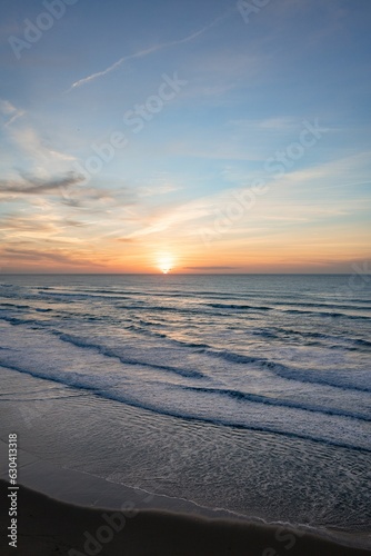 Scenic view of the waves splashing on the sandy beach at sunset