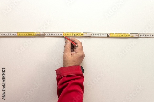 Male measuring a wall with a tape measure ruler for construction or renovation purposes