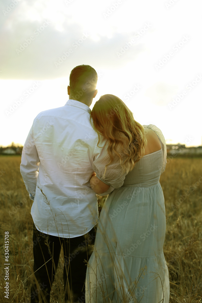 Ein verliebtes Paar steht im Feld und genießt den Sonnenuntergang
