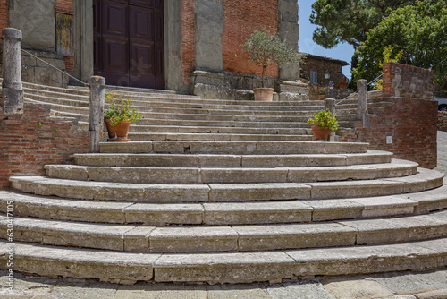 Lucignano, Italy - 23 of May 2022: Walking streets small historic town Lucignano in Tuscany, Italy. View of church "Collegiata di San Michele Arcangelo" facade.