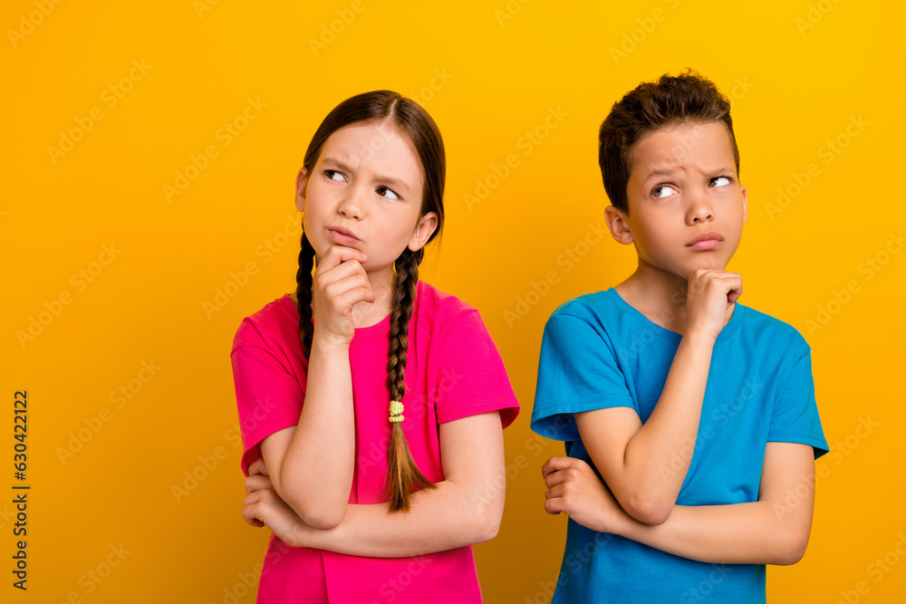 Photo of sweet doubtful preteen schoolchildren wear t-shirts hands arms chins looking empty space isolated yellow color background Photo of sweet doubtful preteen schoolchildren wear t-shirts hands arms chins looking empty space isolated yellow color background
