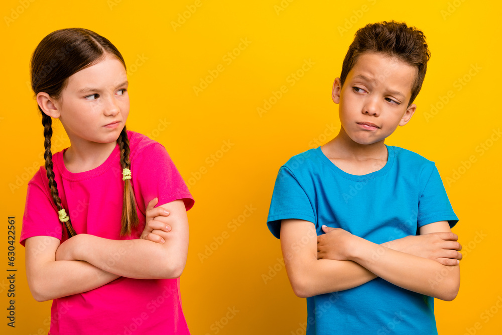 Photo of doubtful unsure preteen schoolchildren wear t-shirts arms crossed having quarrel isolated yellow color background Photo of doubtful unsure preteen schoolchildren wear t-shirts arms crossed having quarrel isolated yellow color background