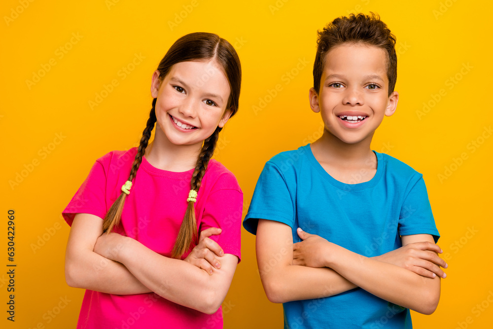 Photo of confident cool preteen schoolchildren wear t-shirts smiling arms crossed isolated yellow color background Photo of confident cool preteen schoolchildren wear t-shirts smiling arms crossed isolated yellow color background