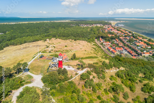 Aerial drone image of Vlieland. With bright red Lighthouse on top of a dune overlooking the town and the Wadden Sea photo