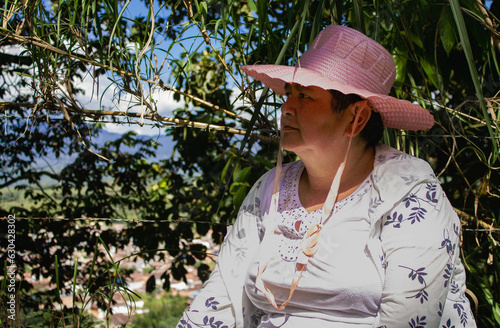 Mujer blanca con sombrero rosado en el campo.