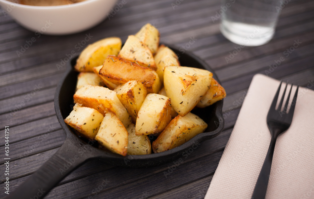 Slices of fried potatoes on cast iron snack pan
