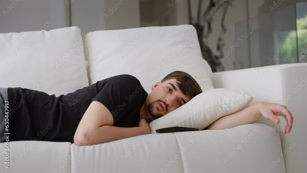 Young man watching tv and falling asleep lying on the couch. Young man watching tv and falling asleep lying on the couch.