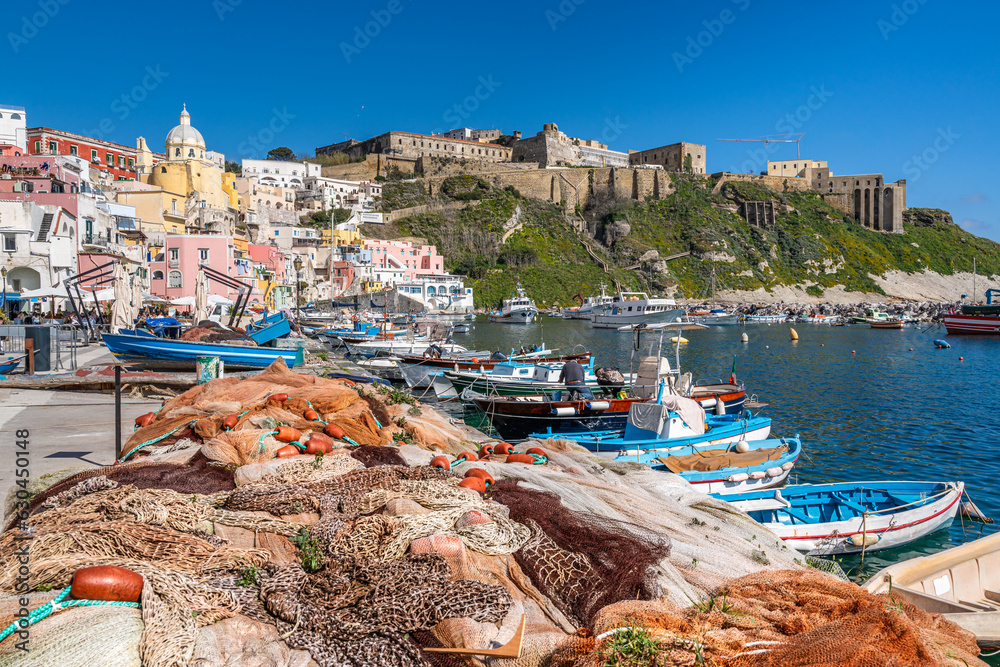 Fish nets and colorful fishing boats moored at Corricella port in Procida, Campania, Italy