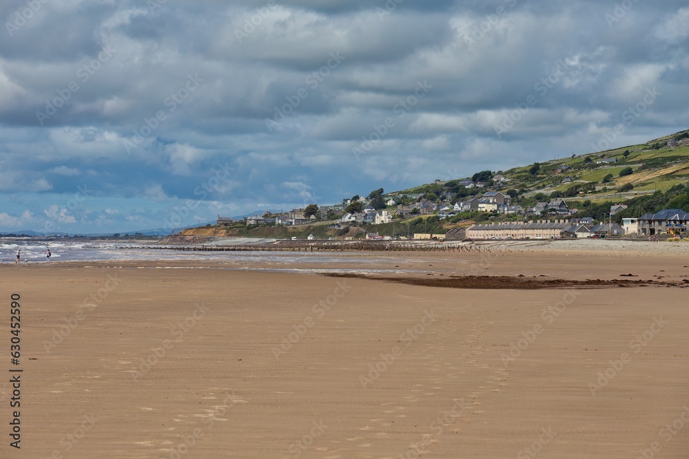 view from the beach to a hill with buildings and the sea in Barmouth, UK