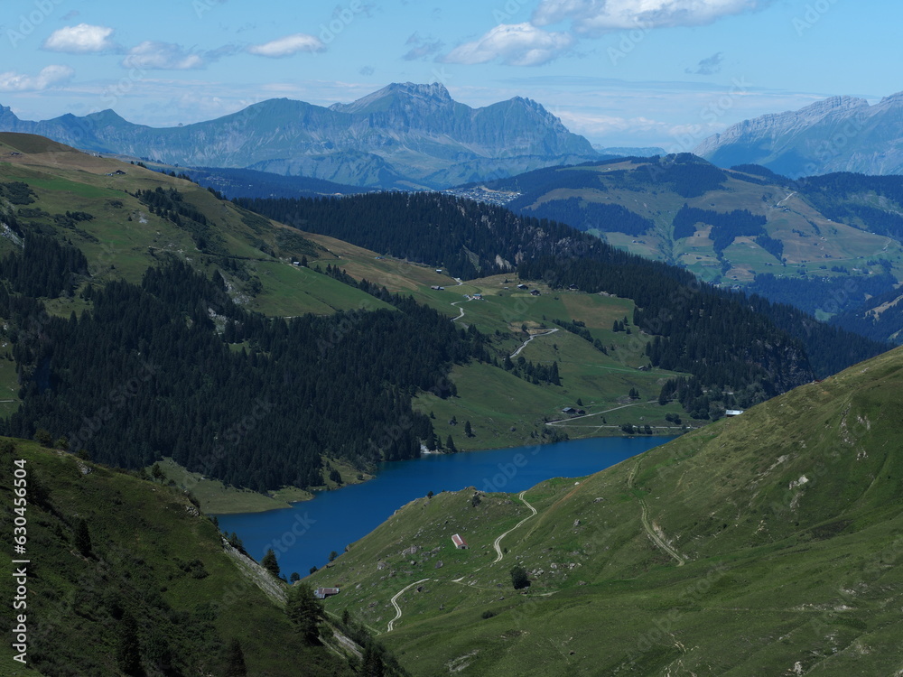 Lac de Roselend et chaîne des Aravis, massif du beaufortain, alpes françaises. Ciel bleu, alpages, forêts, lac, paysage.