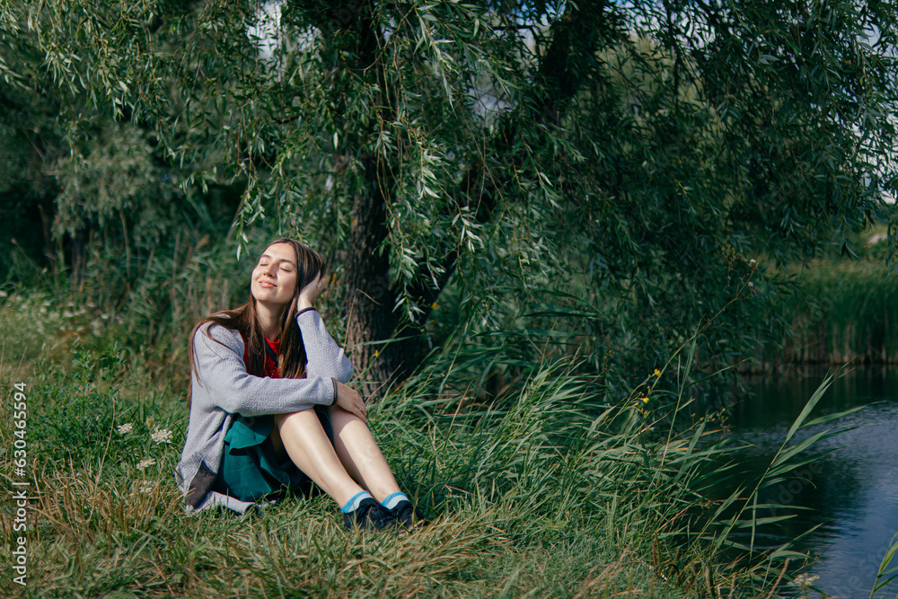 young woman sits on the bank of the river and thinks.Mysterious girl thinks and dreams.positive photo.beautiful self-confident woman. joyful and inspired.feels freedom.Loneliness,thoughts and dreams. young woman sits on the bank of the river and thinks.Mysterious girl thinks and dreams.positive photo.beautiful self-confident woman. joyful and inspired.feels freedom.Loneliness,thoughts and dreams.