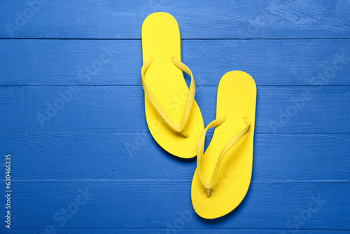 Yellow flip-flops on blue wooden background