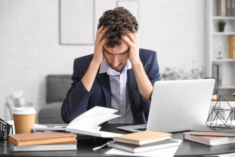 Stressed young businessman working at table in office Stressed young businessman working at table in office