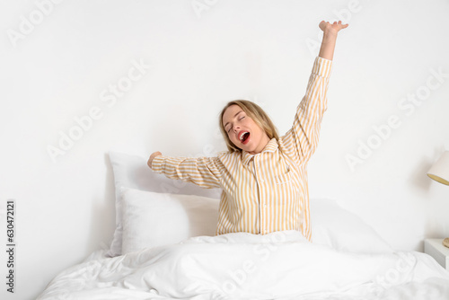 Young woman yawning in bedroom