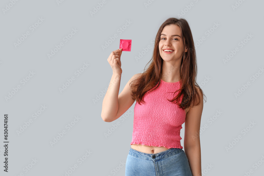 Young woman with condom on light background Young woman with condom on light background
