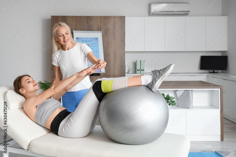 Obraz premium Female physiotherapist working with young woman on couch in rehabilitation center