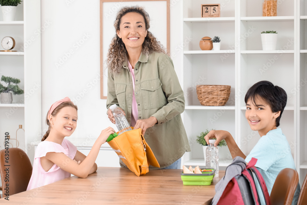 Mother with her little children packing school lunch in kitchen