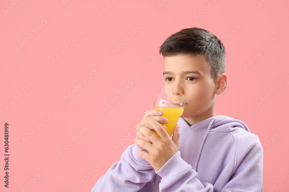 Little boy drinking orange juice on pink background Little boy drinking orange juice on pink background