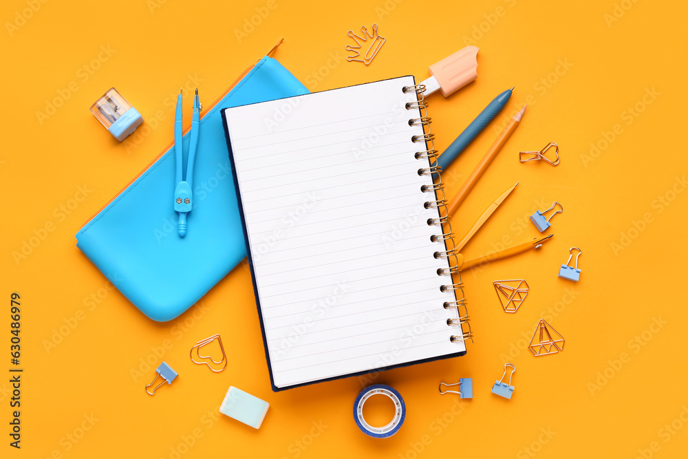 Notebook and pencil case with different stationery supplies on orange background Notebook and pencil case with different stationery supplies on orange background