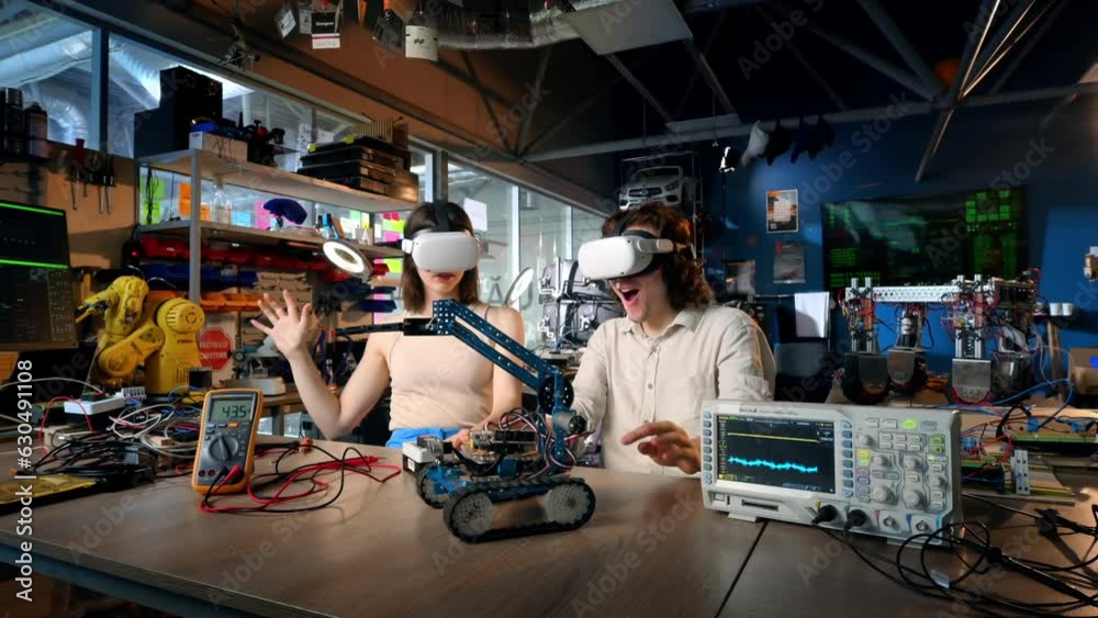Young man and woman in protective glasses doing experiments with electricity in a laboratory. Tools on the table Young man and woman in protective glasses doing experiments with electricity in a laboratory. Tools on the table