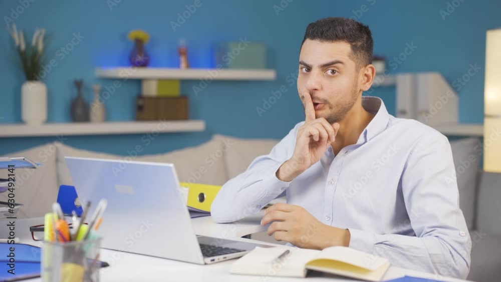 Home office worker man says shhh to camera. Home office worker man says shhh to camera.