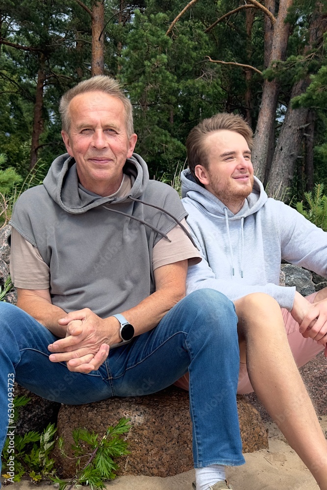 Portrait of young man son and his senior happy father walk together Portrait of young man son and his senior happy father walk together
