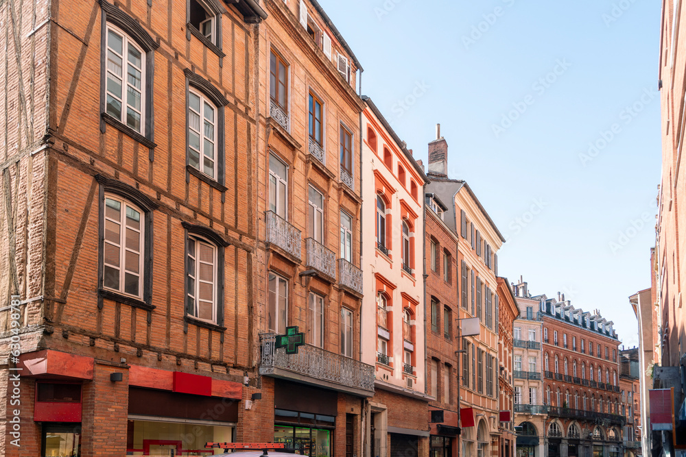 Facade or exterior of historic traditional houses in red or orange in the old city of Toulouse, France