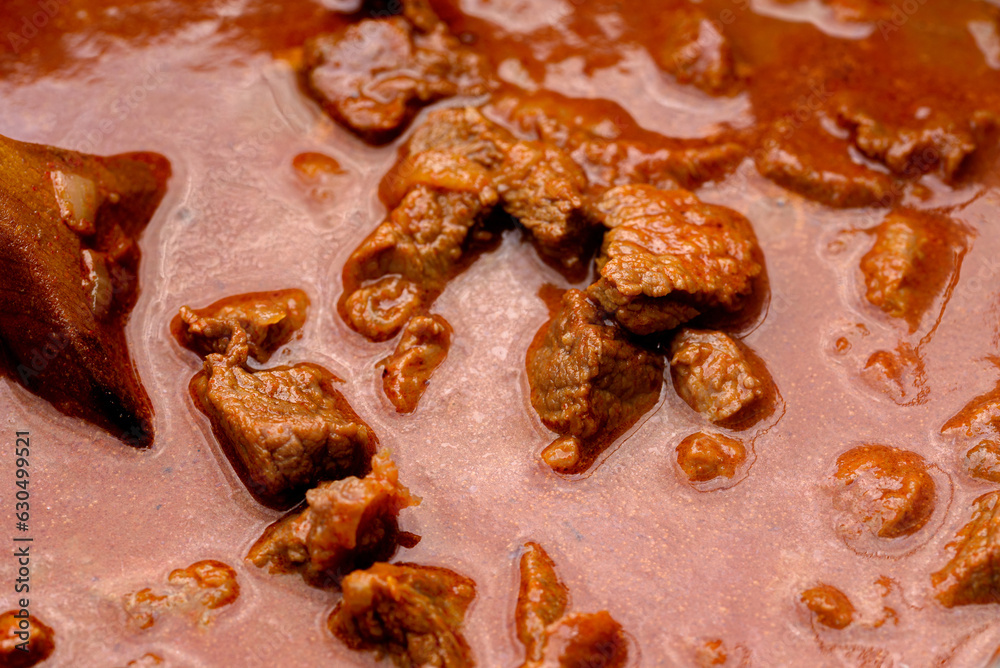 Obraz premium Traditional goulash soup is cooking in the a cauldron.