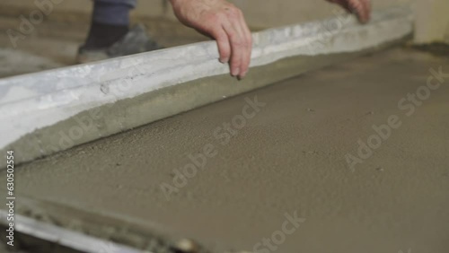 The worker is leveling the surface. Leveling the floor with a screed in the room. Close-up