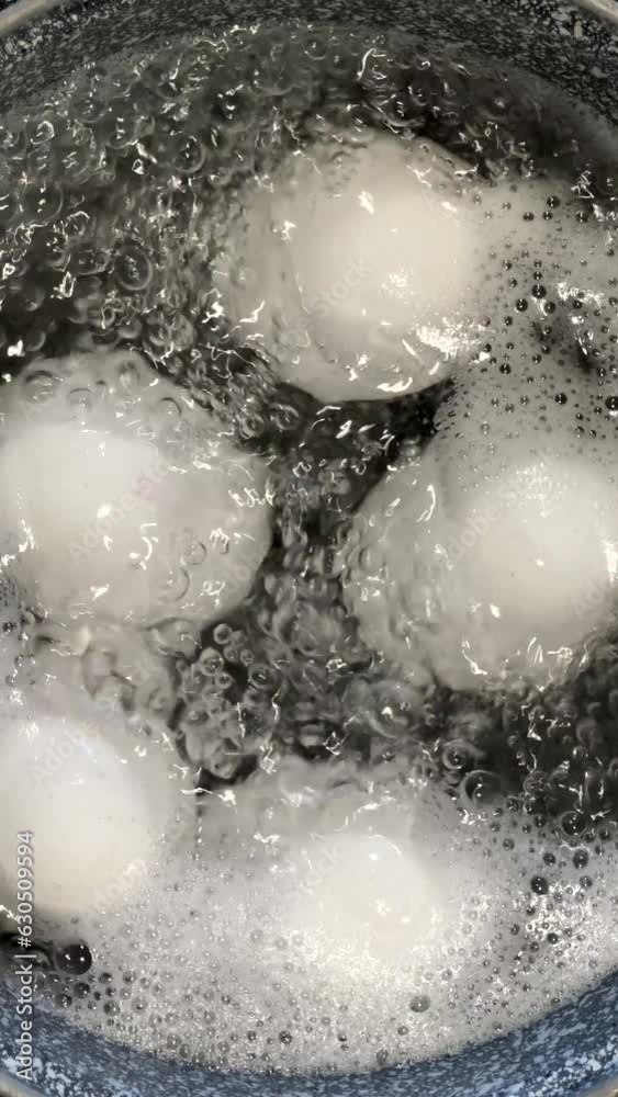 Chicken eggs are boiled in a steel pot on the built-in cooker. Boiled egg. Vertical