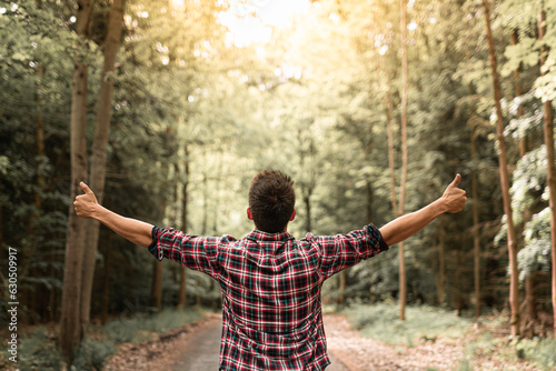 Young man in autumn forest raising arms, expressing carefree happiness and connection with nature.