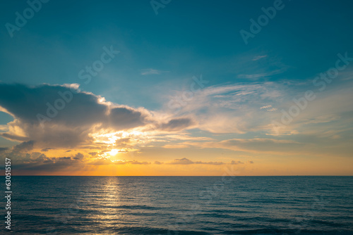 Sunset on tropical beach sea ocean with sunrise clouds. Banner for travel vacation. Scenery sky and reflection rays in water. Dusk, twilight on sea. Seascape in summer morning.
