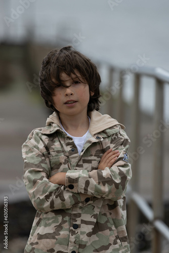 11 years old boy in a military style jacket background blur