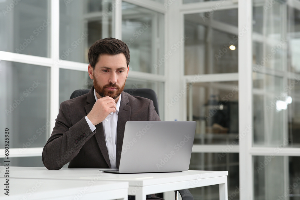 Man working on laptop at white desk in office. Space for text Man working on laptop at white desk in office. Space for text
