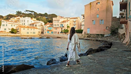 Beautiful girl enjoys the sunset in Cote d'Azur, a coastal town on the French Riviera. Young woman explores historical colorful Old Town of Saint Tropez, a popular resort on the Mediterranean Sea. 
